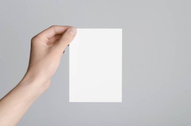 A6 el ilanı / kart / davet Mock-Up - erkek eller gri bir arka plan üzerinde boş bir el ilanı holding.