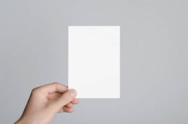 A6 el ilanı / kart / davet Mock-Up - erkek eller gri bir arka plan üzerinde boş bir el ilanı holding.