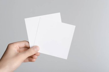 Kare el ilanı / davet Mock-Up - boş el ilanları gri bir arka plan üzerinde tutan eller erkek.