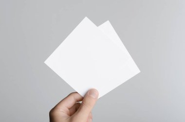 Kare el ilanı / davet Mock-Up - boş el ilanları gri bir arka plan üzerinde tutan eller erkek.
