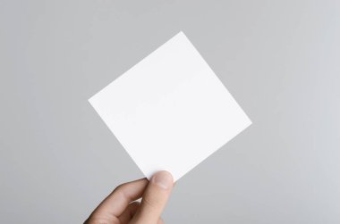 Kare el ilanı / davet Mock-Up - erkek eller gri bir arka plan üzerinde boş bir el ilanı holding.