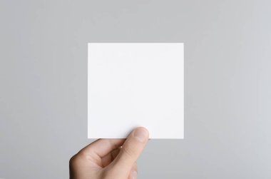 Kare el ilanı / davet Mock-Up - erkek eller gri bir arka plan üzerinde boş bir el ilanı holding.