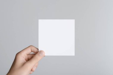 Kare el ilanı / davet Mock-Up - erkek eller gri bir arka plan üzerinde boş bir el ilanı holding.