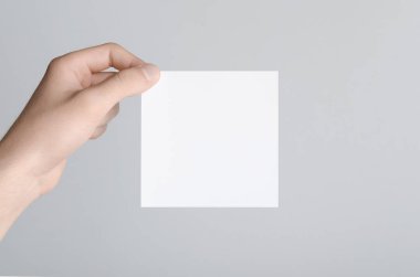 Kare el ilanı / davet Mock-Up - erkek eller gri bir arka plan üzerinde boş bir el ilanı holding.