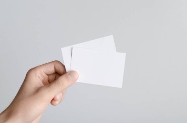 Kartvizit Mock-Up (85x55mm) - erkek gri bir arka plan üzerinde boş kart tutan eller.