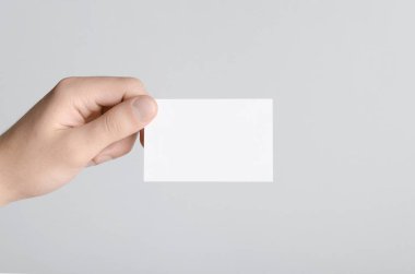 Kartvizit Mock-Up (85x55mm) - erkek gri bir arka plan üzerinde boş bir kart tutan eller.