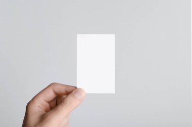 Kartvizit Mock-Up (85x55mm) - erkek gri bir arka plan üzerinde boş bir kart tutan eller.