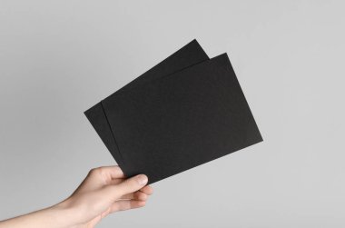 Siyah A5 broşürü / davet Mock-Up - erkek eller gri bir arka plan üzerinde siyah flyers holding.