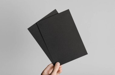 Siyah A5 broşürü / davet Mock-Up - erkek eller gri bir arka plan üzerinde siyah flyers holding.