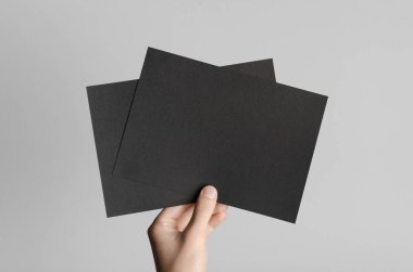 Siyah A5 broşürü / davet Mock-Up - erkek eller gri bir arka plan üzerinde siyah flyers holding.