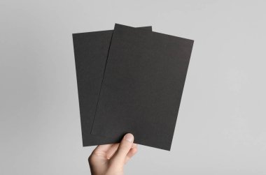 Siyah A5 broşürü / davet Mock-Up - erkek eller gri bir arka plan üzerinde siyah flyers holding.
