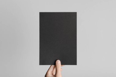 Siyah A5 broşürü / davet Mock-Up - erkek eller gri bir arka plan üzerinde siyah bir el ilanı holding.