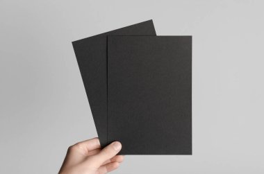 Siyah A5 broşürü / davet Mock-Up - erkek eller gri bir arka plan üzerinde siyah flyers holding.