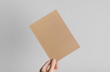 Kraft A5 broşürü / davet Mock-Up - kraft el ilanı gri bir arka plan üzerinde tutan eller erkek.