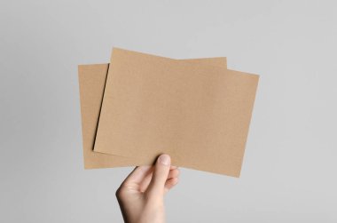 Kraft A5 broşürü / davet Mock-Up-kraft el ilanları gri bir arka plan üzerinde holding erkek eller.