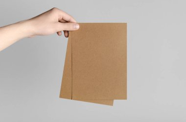 Kraft A5 broşürü / davet Mock-Up-kraft el ilanları gri bir arka plan üzerinde holding erkek eller.