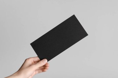 Siyah Dl el ilanı Mock-Up-gri bir arka plan üzerinde siyah bir el ilanı holding erkek eller.