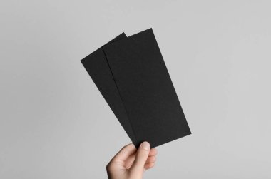 Siyah Dl el ilanı Mock-Up-gri bir arka plan üzerinde siyah flyers holding erkek eller.