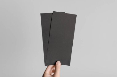 Siyah Dl el ilanı Mock-Up-gri bir arka plan üzerinde siyah flyers holding erkek eller.