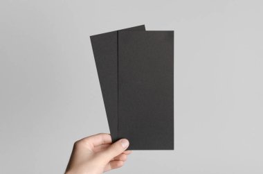 Siyah Dl el ilanı Mock-Up-gri bir arka plan üzerinde siyah flyers holding erkek eller.