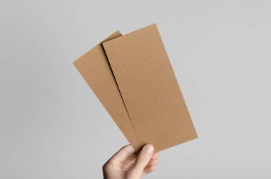 Kraft Dl el ilanı Mock-Up-kraft el ilanları gri bir arka plan üzerinde holding erkek eller.