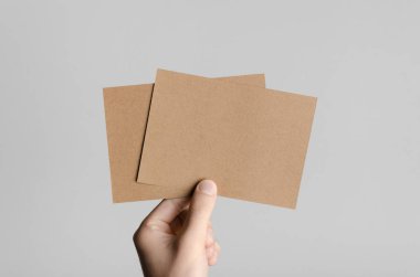 Kraft A6 el ilanı / kart / davet Mock-Up-kraft el ilanları gri bir arka plan üzerinde holding erkek eller.