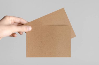 Kraft A6 el ilanı / kart / davet Mock-Up-kraft el ilanları gri bir arka plan üzerinde holding erkek eller.