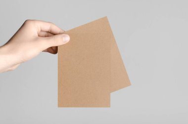 Kraft A6 el ilanı / kart / davet Mock-Up-kraft el ilanları gri bir arka plan üzerinde holding erkek eller.