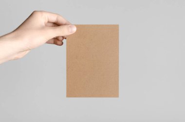 Kraft A6 el ilanı / kart / davet Mock-Up - kraft el ilanı gri bir arka plan üzerinde tutan eller erkek.