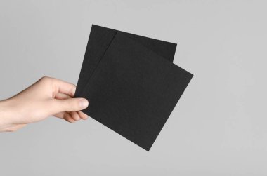 Siyah kare el ilanı / davet Mock-Up - erkek eller gri bir arka plan üzerinde siyah flyers holding.