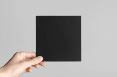 Siyah kare el ilanı / davet Mock-Up - erkek eller gri bir arka plan üzerinde siyah bir el ilanı holding.