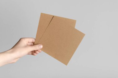 Kraft kare el ilanı / davet Mock-Up-kraft el ilanları gri bir arka plan üzerinde holding erkek eller.