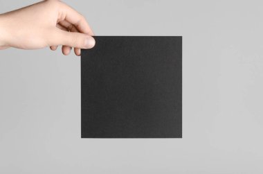 Siyah kare el ilanı / davet Mock-Up - erkek eller gri bir arka plan üzerinde siyah bir el ilanı holding.