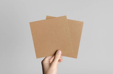 Kraft kare el ilanı / davet Mock-Up-kraft el ilanları gri bir arka plan üzerinde holding erkek eller.