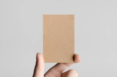 Kraft kartvizit Mock-Up (85x55mm) - kraft kartı gri bir arka plan üzerinde holding erkek eller.