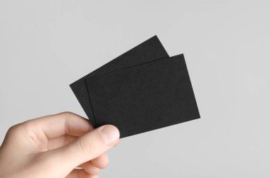 Siyah kartvizit Mock-Up (85x55mm) - erkek gri bir arka plan üzerinde boş kart tutan eller.