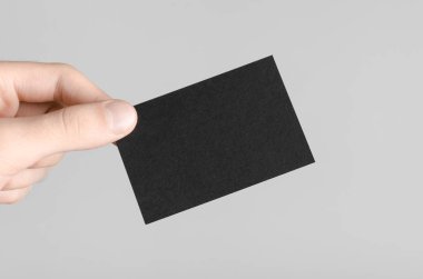 Siyah kartvizit Mock-Up (85x55mm) - erkek gri bir arka plan üzerinde boş bir kart tutan eller.