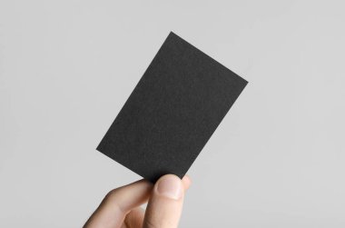 Siyah kartvizit Mock-Up (85x55mm) - erkek gri bir arka plan üzerinde boş bir kart tutan eller.