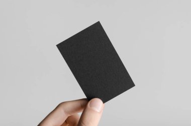 Siyah kartvizit Mock-Up (85x55mm) - erkek gri bir arka plan üzerinde boş bir kart tutan eller.