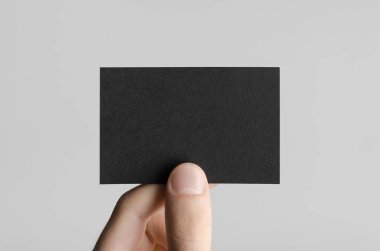 Siyah kartvizit Mock-Up (85x55mm) - erkek gri bir arka plan üzerinde boş bir kart tutan eller.