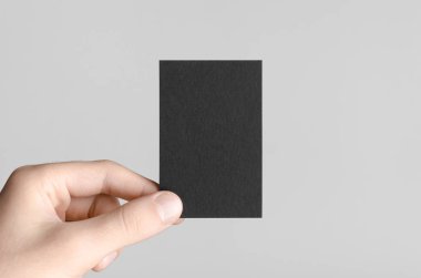 Siyah kartvizit Mock-Up (85x55mm) - erkek gri bir arka plan üzerinde boş bir kart tutan eller.