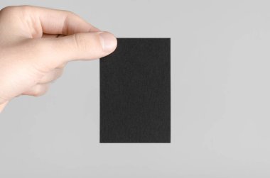 Siyah kartvizit Mock-Up (85x55mm) - erkek gri bir arka plan üzerinde boş bir kart tutan eller.