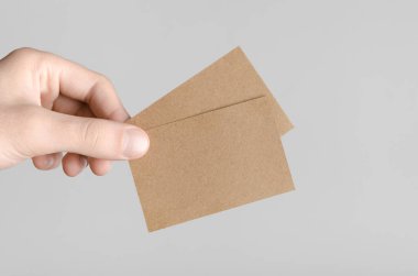 Kraft kartvizit Mock-Up (85x55mm) - kraft kartları gri bir arka plan üzerinde holding erkek eller.