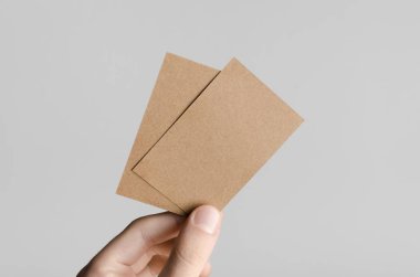 Kraft kartvizit Mock-Up (85x55mm) - kraft kartları gri bir arka plan üzerinde holding erkek eller.