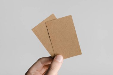 Kraft kartvizit Mock-Up (85x55mm) - kraft kartları gri bir arka plan üzerinde holding erkek eller.