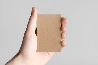 Kraft kartvizit Mock-Up (85x55mm) - kraft kartı gri bir arka plan üzerinde holding erkek eller.
