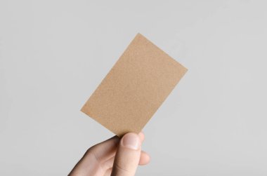 Kraft kartvizit Mock-Up (85x55mm) - kraft kartı gri bir arka plan üzerinde holding erkek eller.