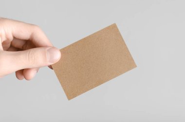 Kraft kartvizit Mock-Up (85x55mm) - kraft kartı gri bir arka plan üzerinde holding erkek eller.