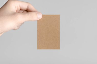 Kraft kartvizit Mock-Up (85x55mm) - kraft kartı gri bir arka plan üzerinde holding erkek eller.