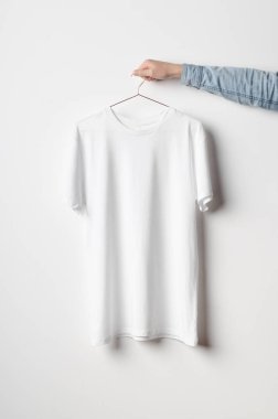 Erkekler mürettebat boyun T-Shirt Mock-Up-beyaz bir t-shirt bir bakır tel elbise askısı üzerinde tutan adam